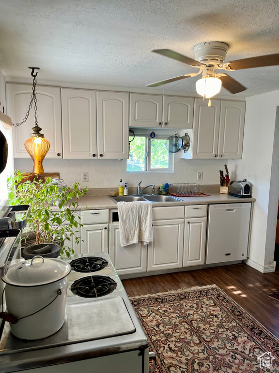 Kitchen featuring dishwashing machine, dark wood finished floors, a sink, white cabinets, and a ceiling fan