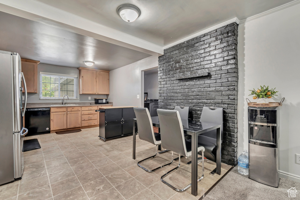 Kitchen featuring light brown cabinets, black appliances, light tile patterned floors, light countertops, and a sink