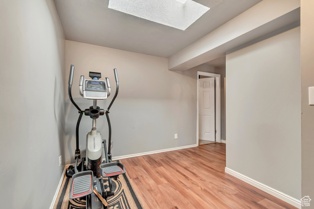 Workout area featuring a skylight, light wood-type flooring, and baseboards