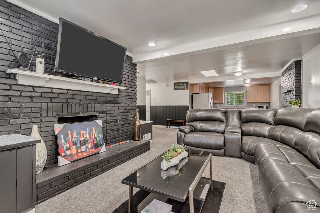 Living area with carpet flooring, a wainscoted wall, a fireplace, and recessed lighting
