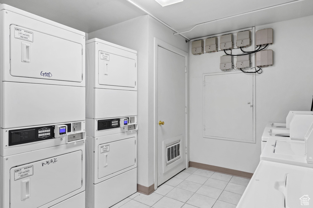 Community laundry room featuring stacked washing machine and dryer and baseboards