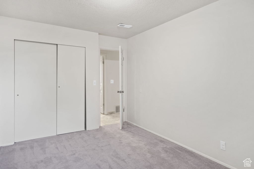 Unfurnished bedroom featuring carpet, a closet, a textured ceiling, and baseboards