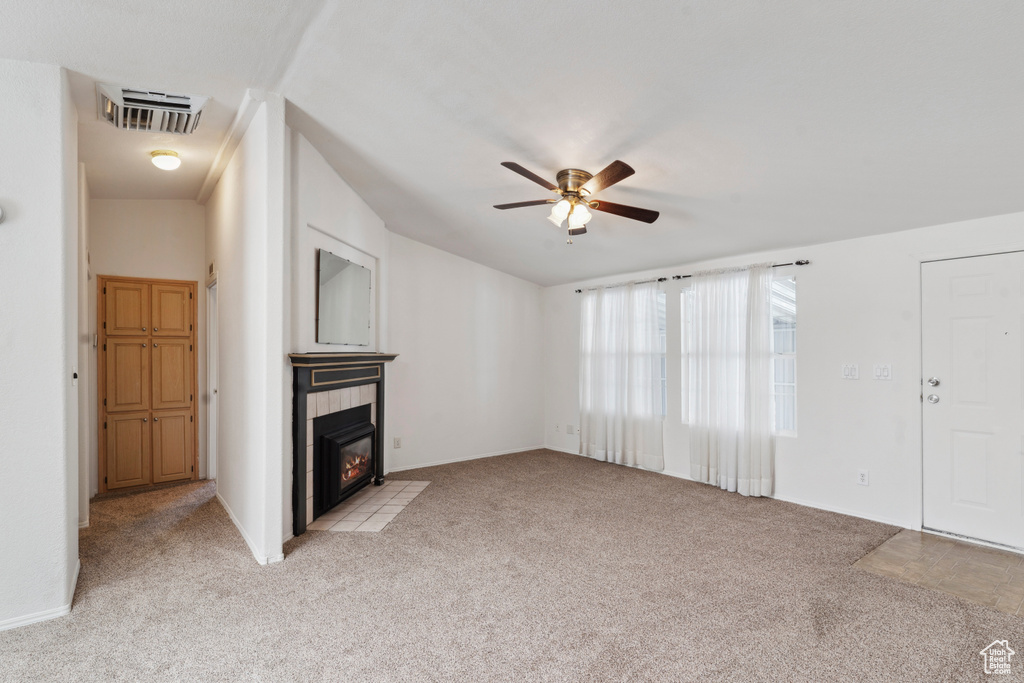 Unfurnished living room with light carpet, ceiling fan, a fireplace, and baseboards