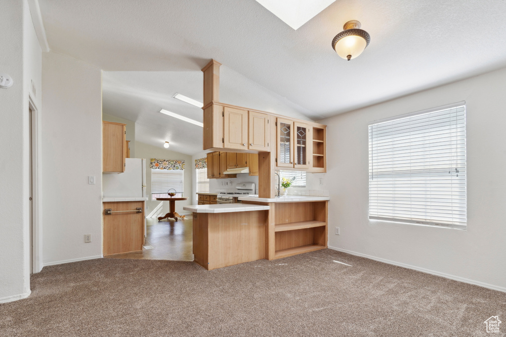 Kitchen featuring white appliances, open shelves, vaulted ceiling, light brown cabinetry, and under cabinet range hood
