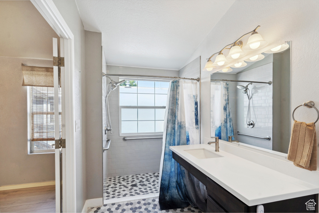 Bathroom with tiled shower, vanity, and baseboards