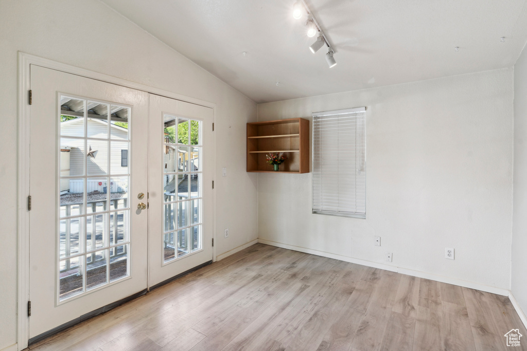 Spare room with light wood-style flooring, track lighting, baseboards, and french doors