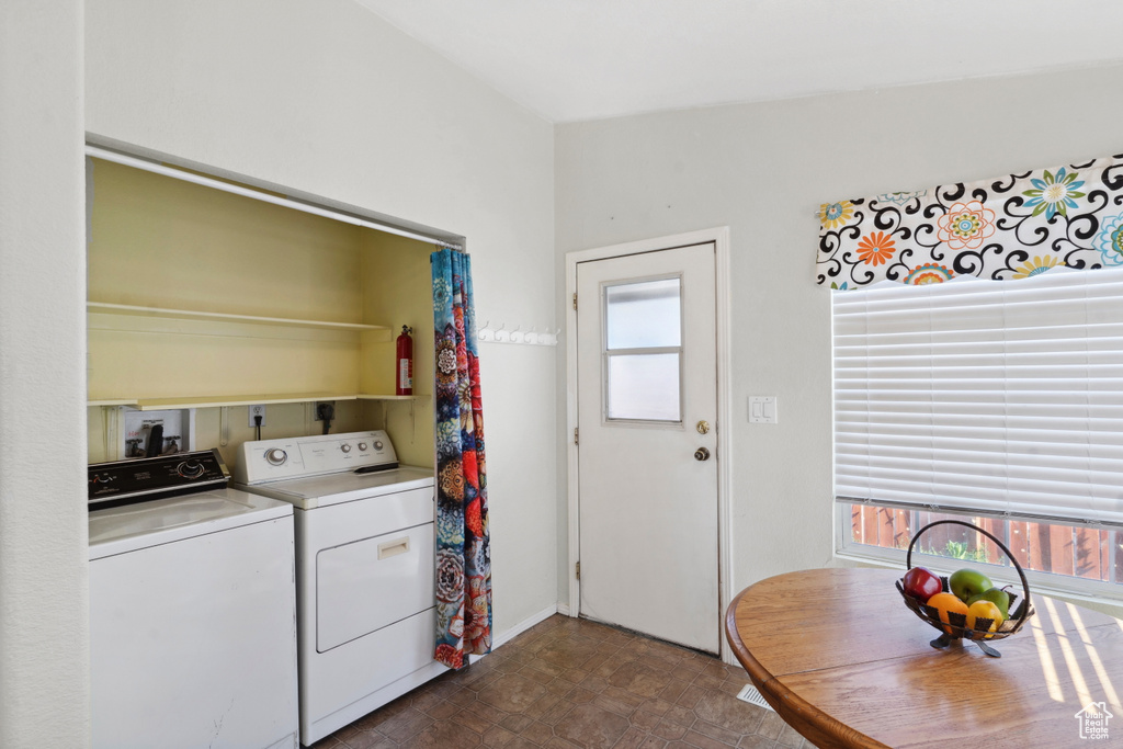 Laundry room featuring washing machine and clothes dryer, healthy amount of natural light, and dark flooring