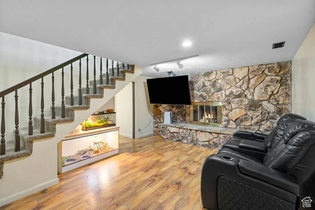 Living room featuring wood finished floors, track lighting, baseboards, and stairway