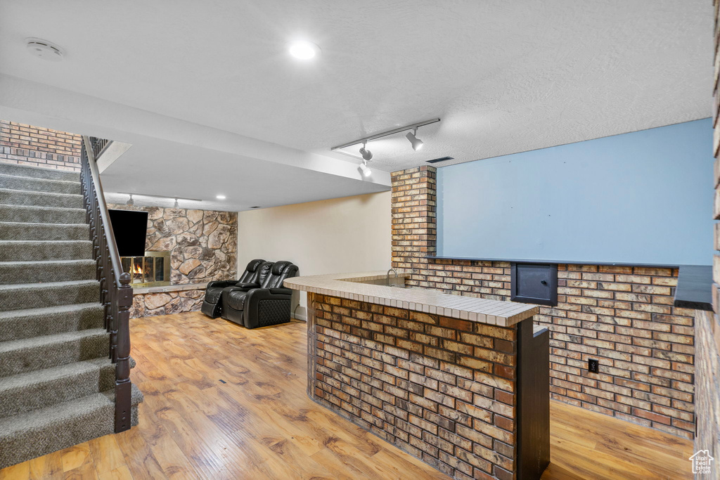 Bar area featuring stairs, light wood-type flooring, a fireplace, and track lighting