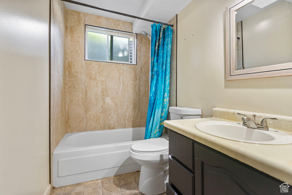 Bathroom featuring toilet, vanity, and shower / bath combination with curtain
