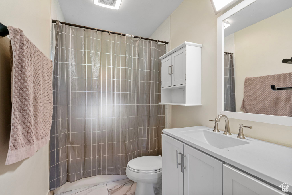 Bathroom with marble look tile flooring, vanity, toilet, and a shower with curtain