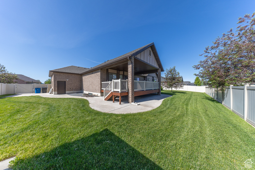 Rear view of house featuring a patio area, brick siding, board and batten siding, and a wooden deck
