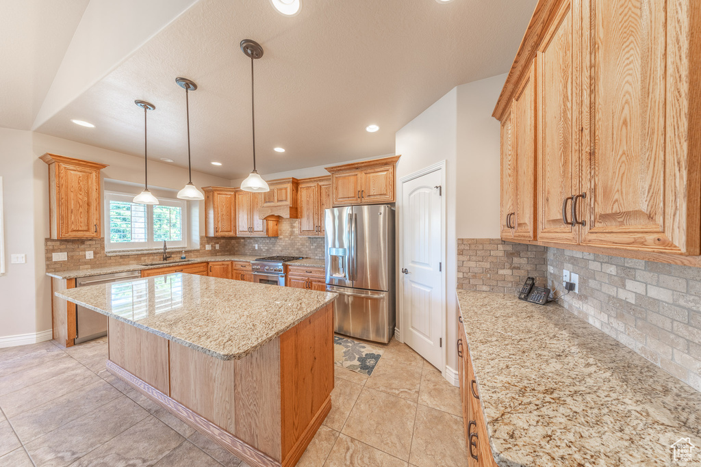 Kitchen with appliances with stainless steel finishes, backsplash, light stone counters, a sink, and recessed lighting