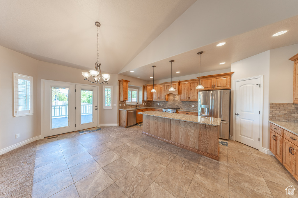 Kitchen with appliances with stainless steel finishes, tasteful backsplash, a kitchen island, light stone countertops, and recessed lighting