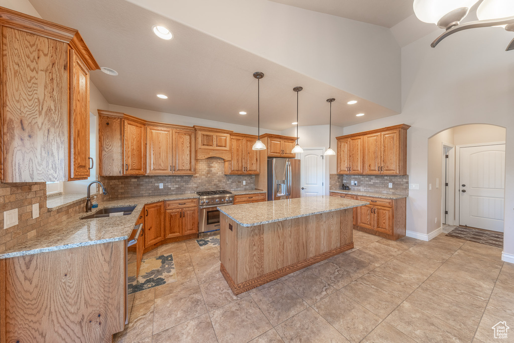 Kitchen with stainless steel appliances, a center island, light stone counters, arched walkways, and backsplash