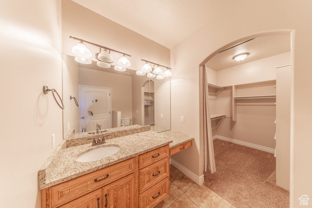 Bathroom featuring vanity, tile patterned flooring, a spacious closet, toilet, and baseboards