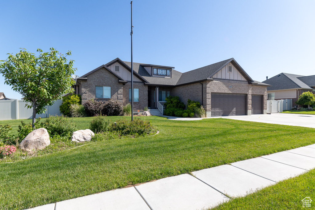 View of front of house featuring an attached garage, brick siding, concrete driveway, and board and batten siding