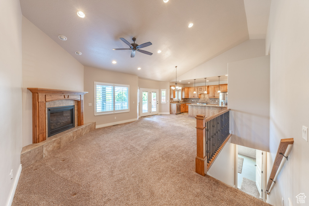 Unfurnished living room featuring light colored carpet, recessed lighting, lofted ceiling, a fireplace, and ceiling fan