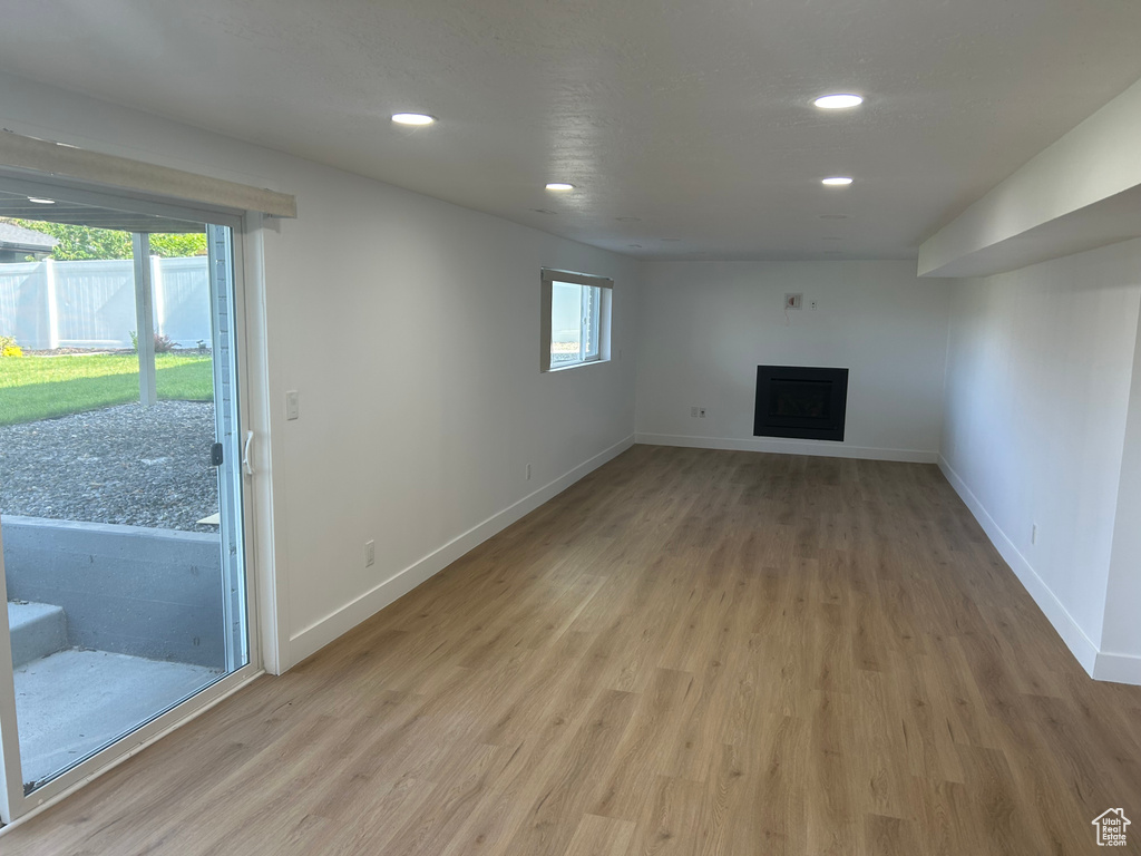 Unfurnished living room featuring light wood finished floors, baseboards, a fireplace, and recessed lighting