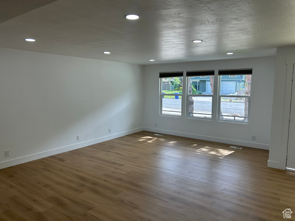 Unfurnished room featuring baseboards, recessed lighting, wood finished floors, and a textured ceiling