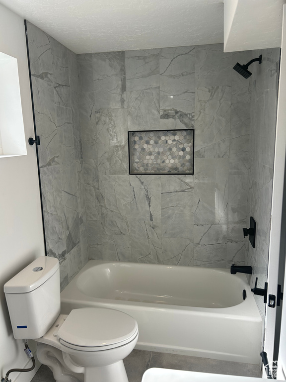 Bathroom with toilet, shower / washtub combination, and a textured ceiling