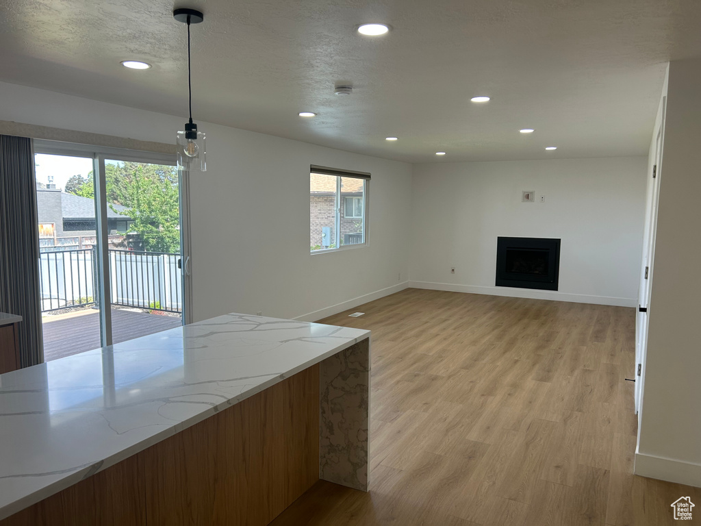 Unfurnished living room featuring light wood-style floors, recessed lighting, baseboards, and a fireplace