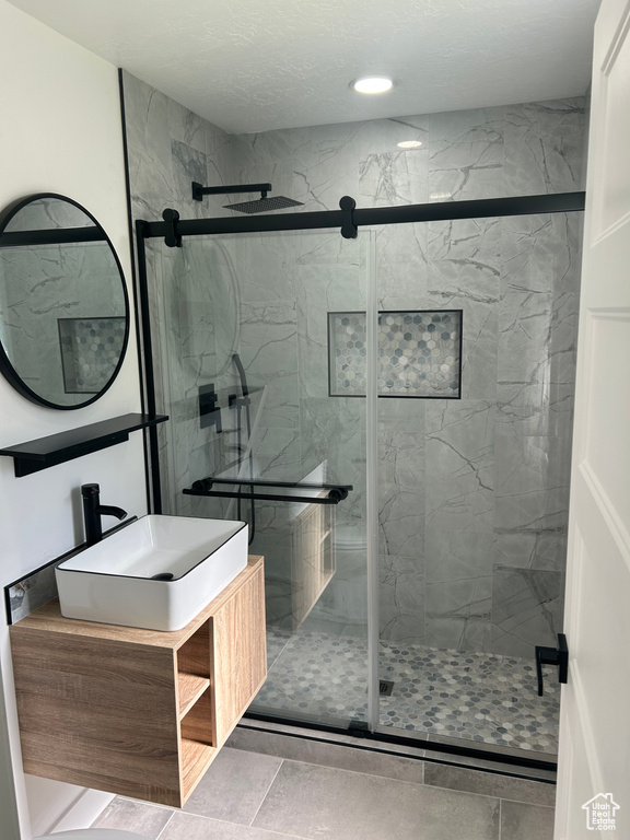 Full bathroom featuring a marble finish shower and vanity