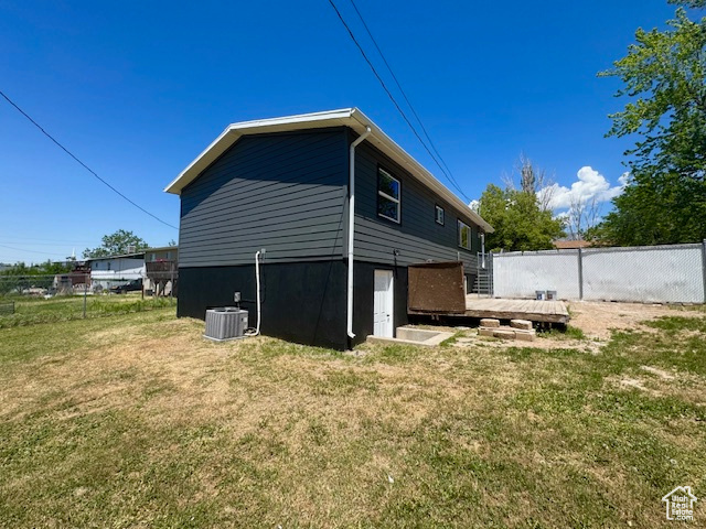 Rear view of property featuring a deck and central AC