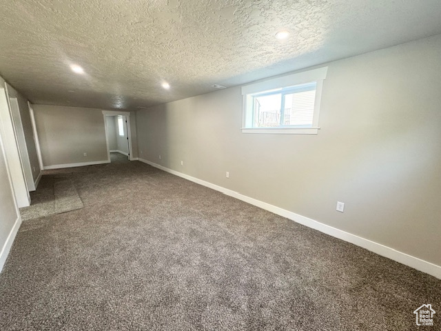 Below grade area featuring a textured ceiling, baseboards, carpet floors, and recessed lighting