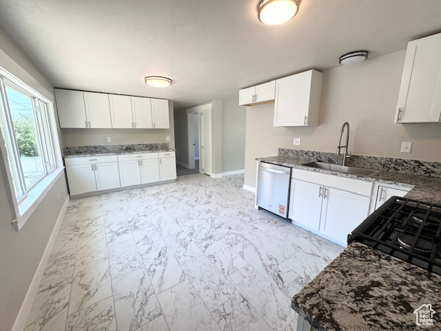 Kitchen featuring dishwasher, a sink, baseboards, light marble finish floors, and white cabinetry