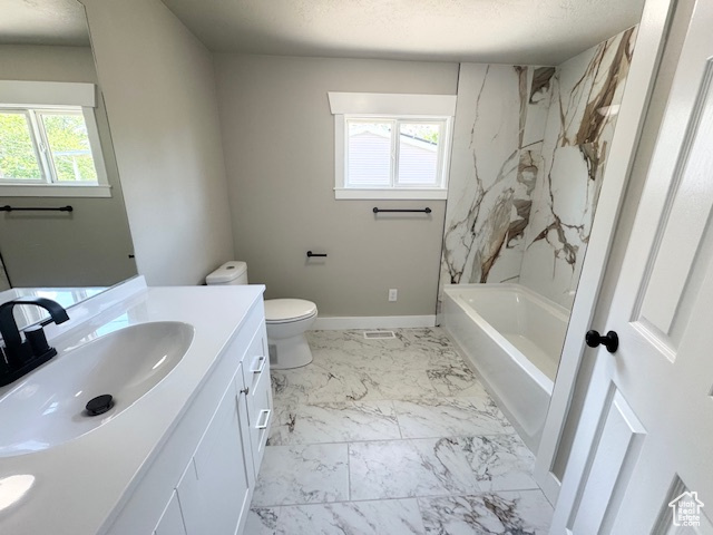 Full bath with vanity, marble finish floors, toilet, shower / washtub combination, and baseboards