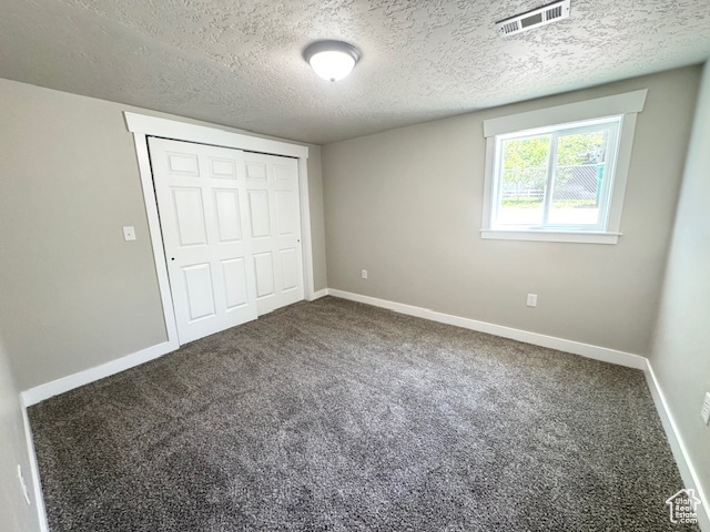 Unfurnished bedroom featuring carpet flooring, a textured ceiling, a closet, and baseboards