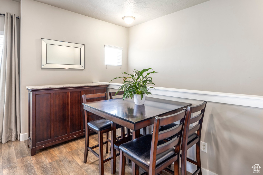Dining area with light wood-style floors, a textured ceiling, and baseboards