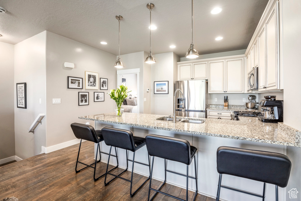 Kitchen featuring appliances with stainless steel finishes, dark wood-style floors, baseboards, a peninsula, and white cabinets