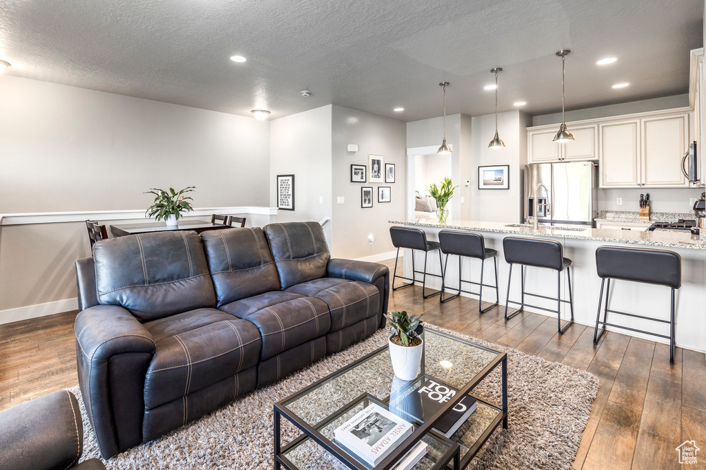 Living area featuring dark wood finished floors, recessed lighting, baseboards, and a textured ceiling