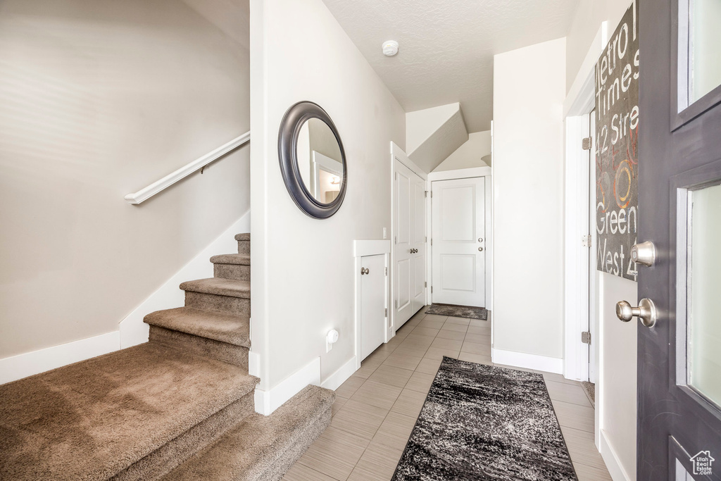 Foyer entrance featuring stairs, tile patterned flooring, and baseboards