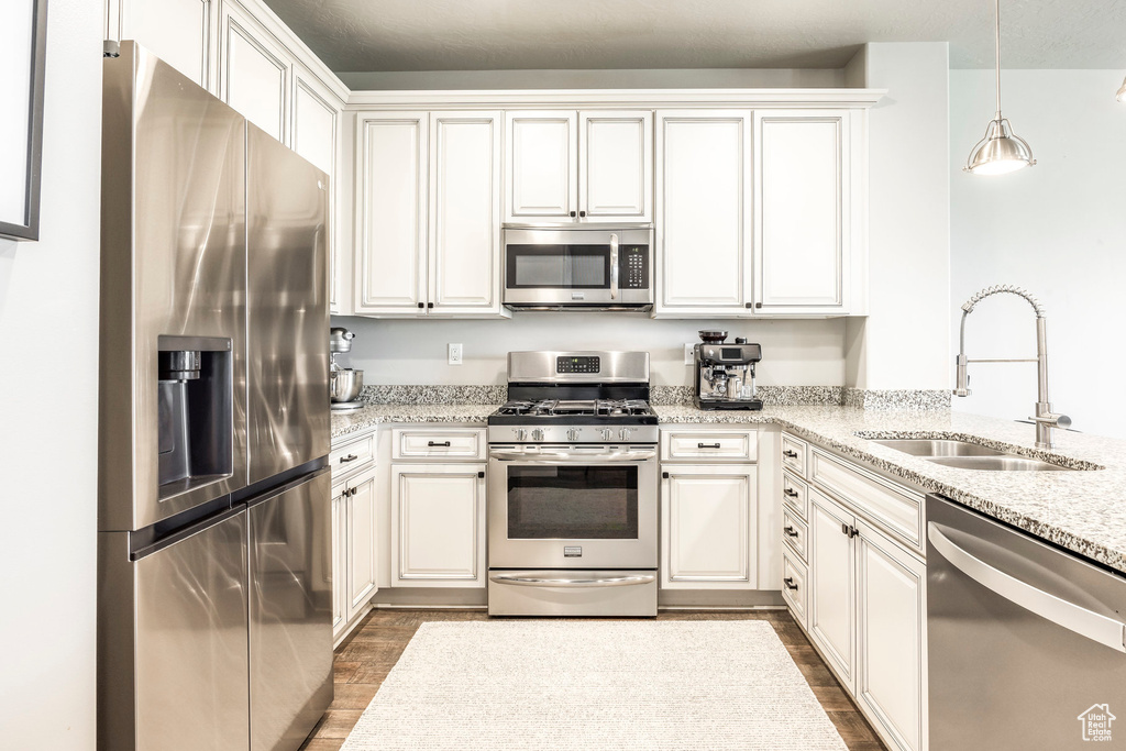 Kitchen featuring appliances with stainless steel finishes, a sink, dark wood-style flooring, and white cabinets