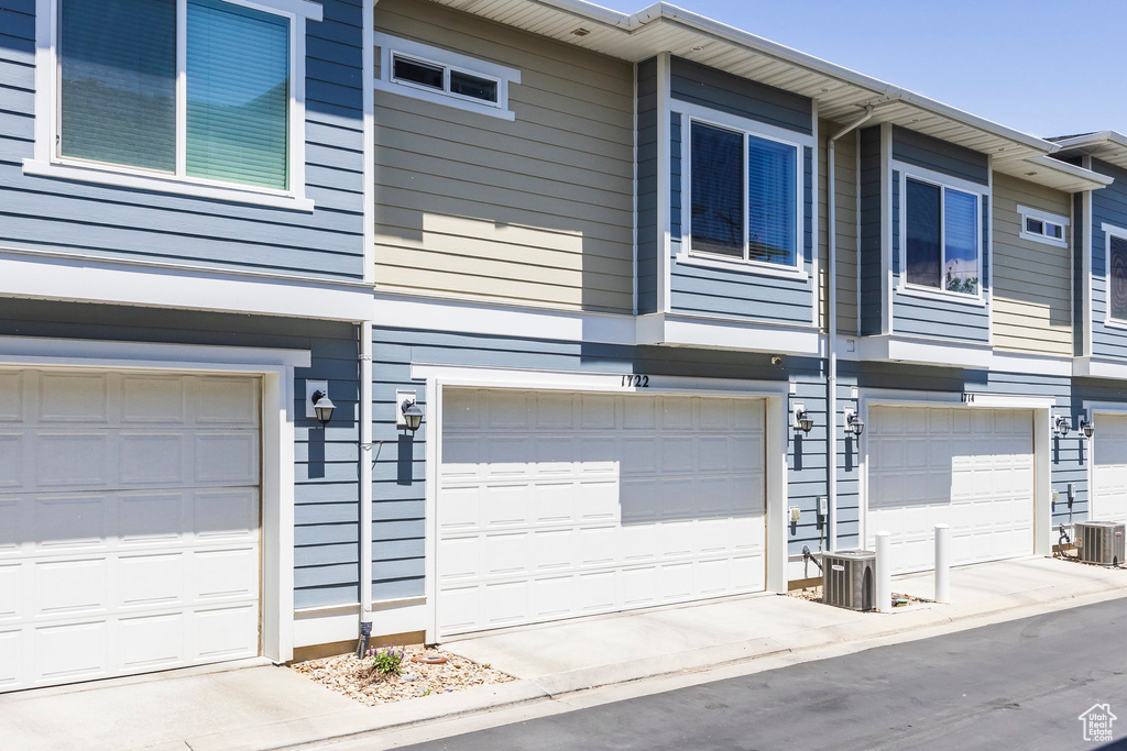View of side of property featuring cooling unit and an attached garage