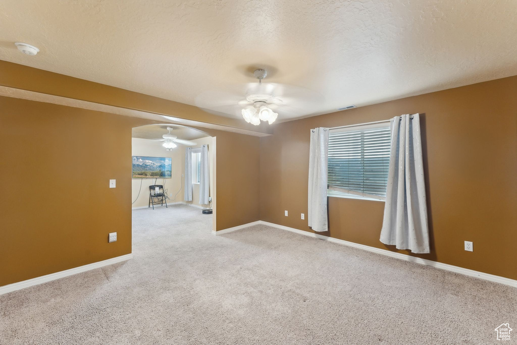 Empty room featuring a ceiling fan, carpet flooring, baseboards, and a smoke detector
