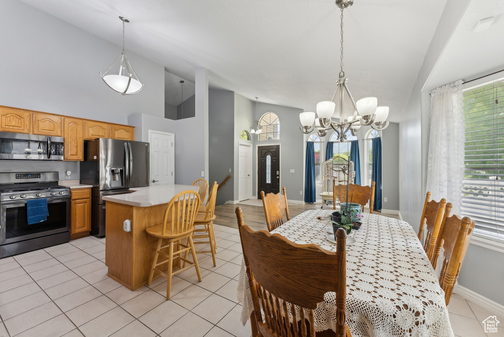 Dining space featuring a chandelier, healthy amount of natural light, baseboards, high vaulted ceiling, and light tile patterned flooring
