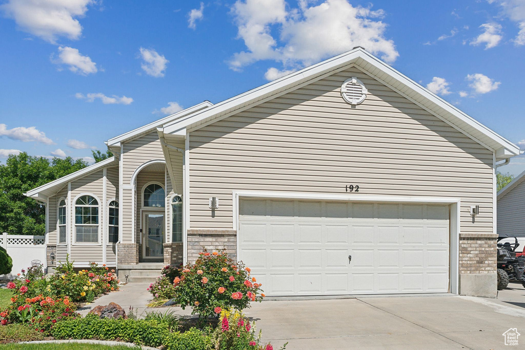 View of front facade featuring brick siding, concrete driveway, and an attached garage