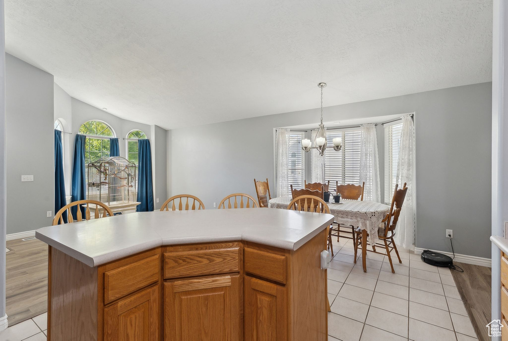 Kitchen featuring a chandelier, light countertops, light tile patterned flooring, pendant lighting, and baseboards