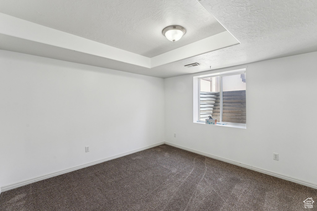 Empty room with a textured ceiling, carpet flooring, and baseboards