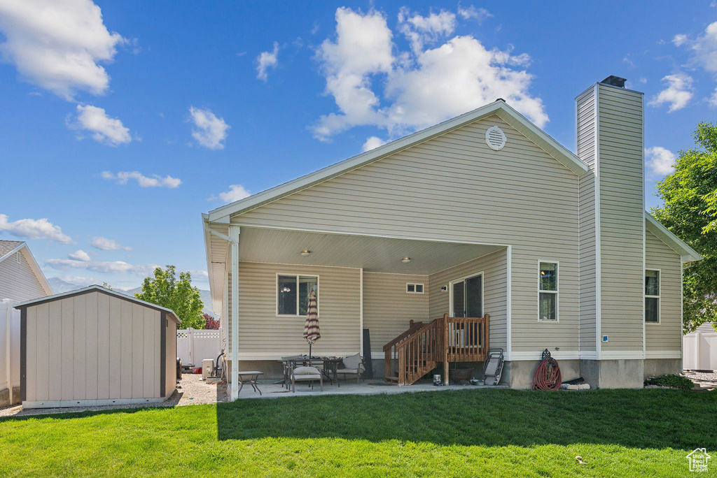 Back of property featuring a patio area, a yard, and a chimney