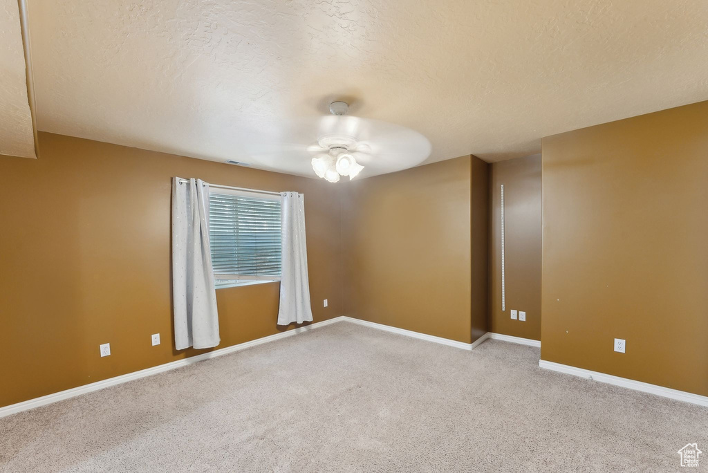 Unfurnished room with light carpet, baseboards, and a textured ceiling