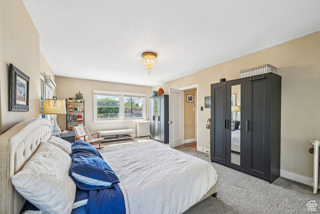 Bedroom with radiator heating unit, carpet, and baseboards