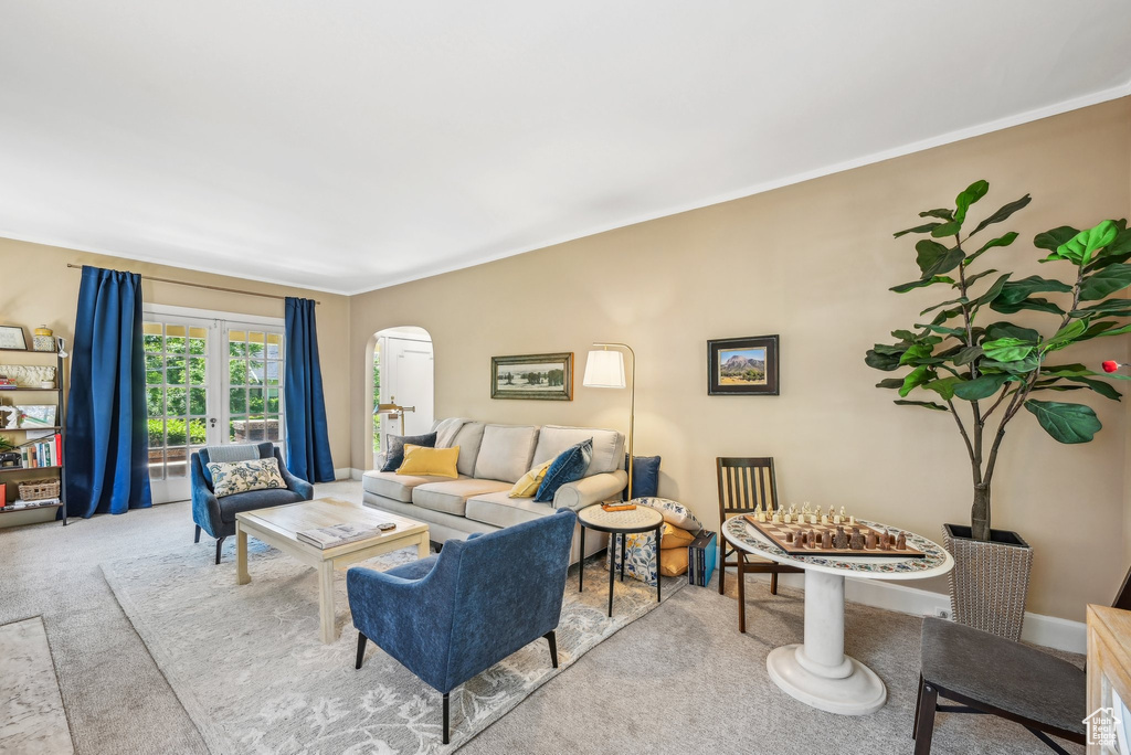Living area with arched walkways, carpet floors, and crown molding
