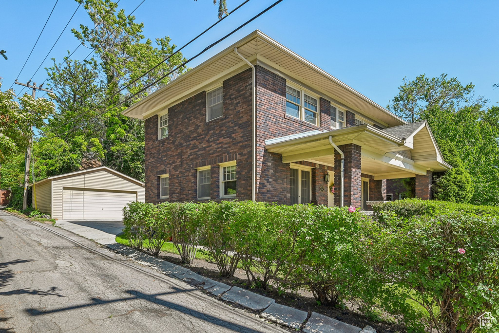 View of front facade with a detached garage, an outbuilding, and brick siding