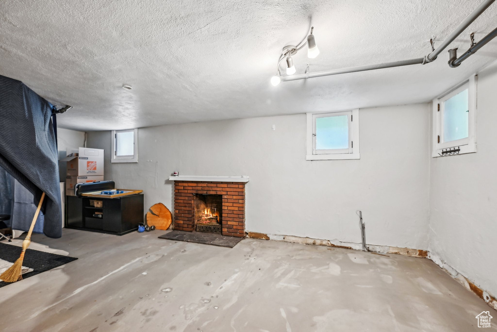 Basement with a brick fireplace, a textured ceiling, and plenty of natural light