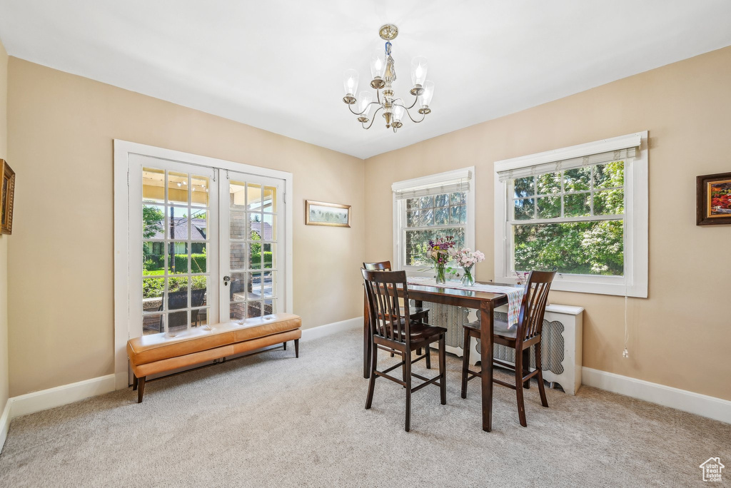Dining area with carpet flooring, a chandelier, and healthy amount of natural light